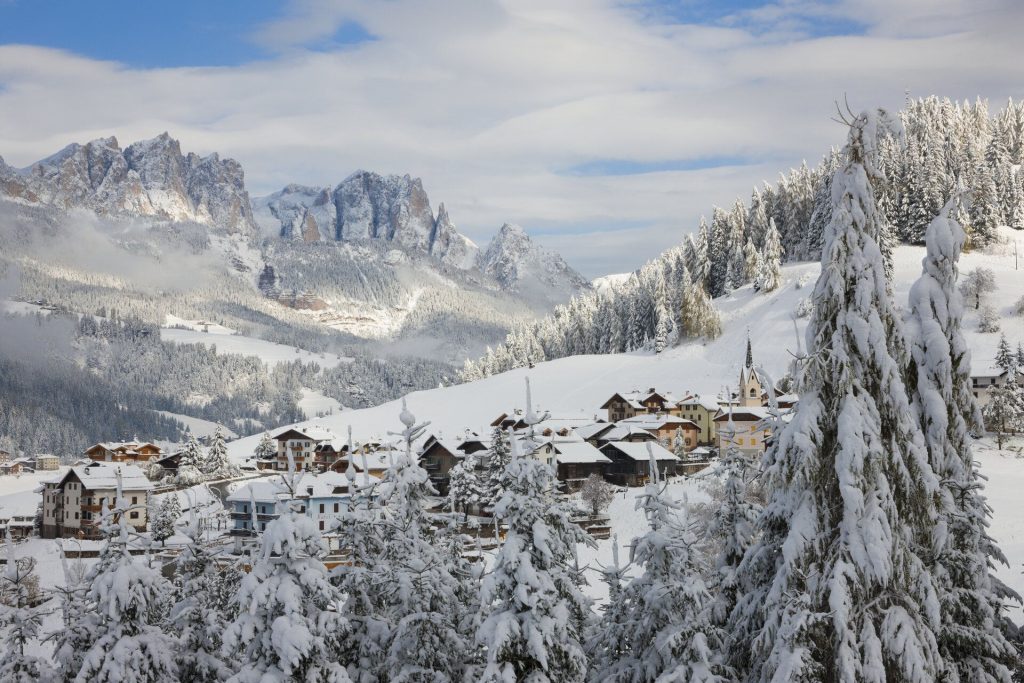 Snow-covered alpine village nestled in a valley with frosty trees and distant mountainson the horizon