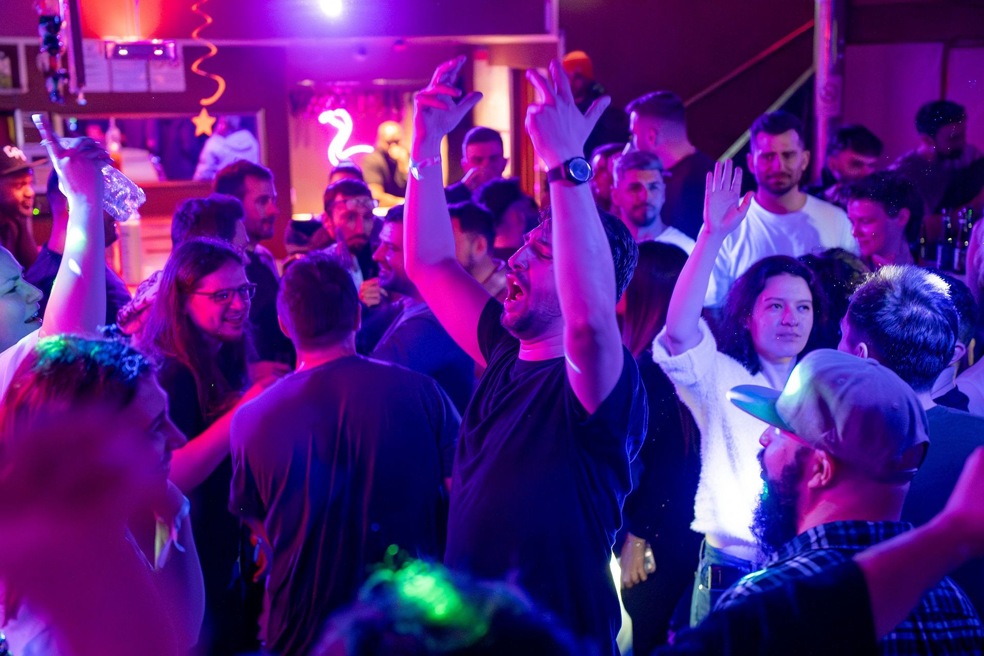 ADR05615-Enhanced-NR snow vars | Fresh Planet | Fresh Planet Crowded nightclub dance floor with colorful purple/pink lights, people raising hands and dancing.