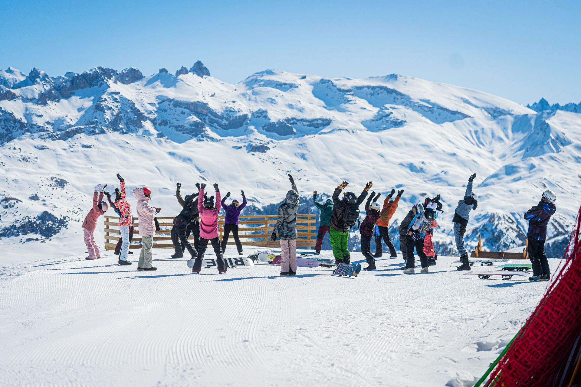 BLJ06600 snow vars | Fresh Planet | Fresh Planet Group of skiers and snowboarders on a snowy slope, arms raised, with snow-covered mountains in the background.