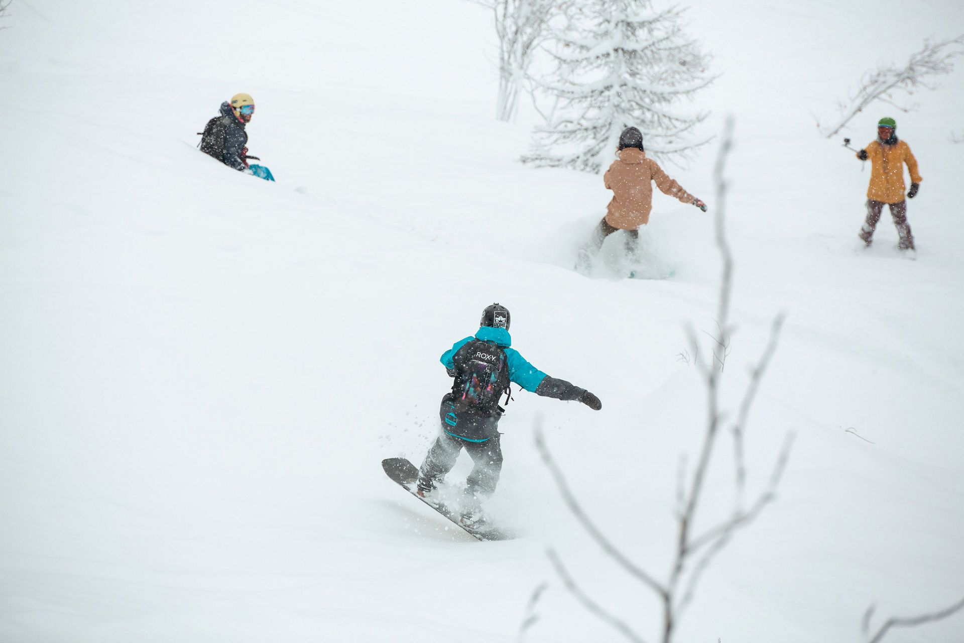 FJ7B8009 snow avoriaz | Fresh Planet | Fresh Planet Snowboarder in teal jacket carving a turn in fresh powder, with other skiers watching in the background.