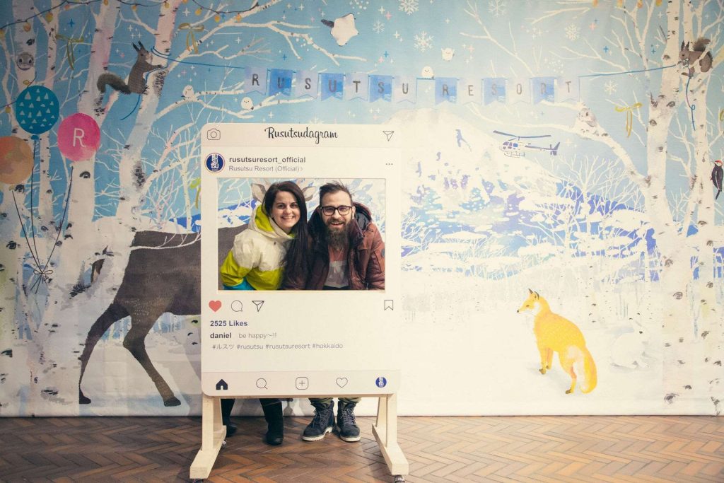 Life-size pretend Instagram post cutout with a smiling couple posing in front of a snowy mural background.